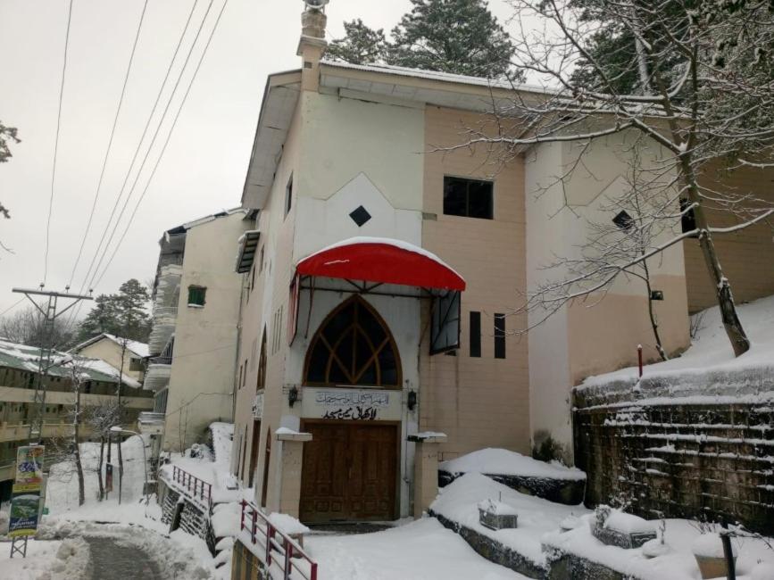 un pequeño edificio con techo rojo en la nieve en Jalwa Residential, en Murree