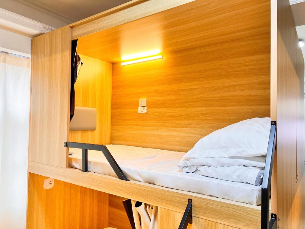 een klein bed in een kleine kamer met een houten muur bij Waveflo Hostel 浪花青旅 in Hong Kong