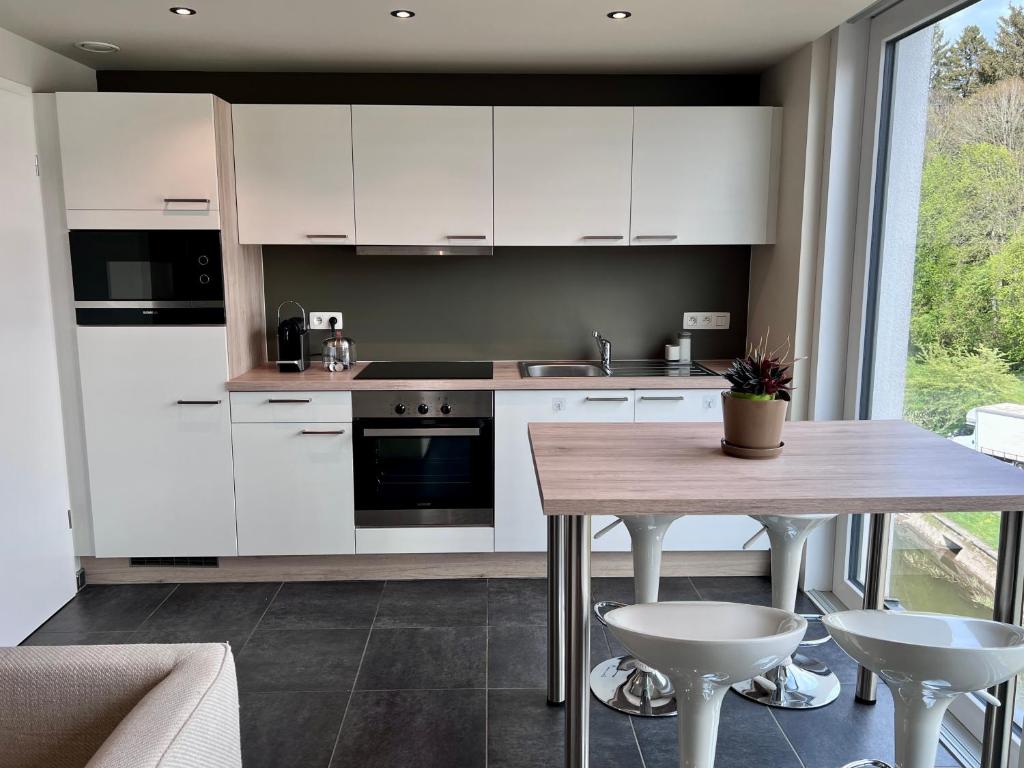 una cucina con armadi bianchi e tavolo in legno di Luxurious flat offering comfort and privacy in Martelange a Martelange