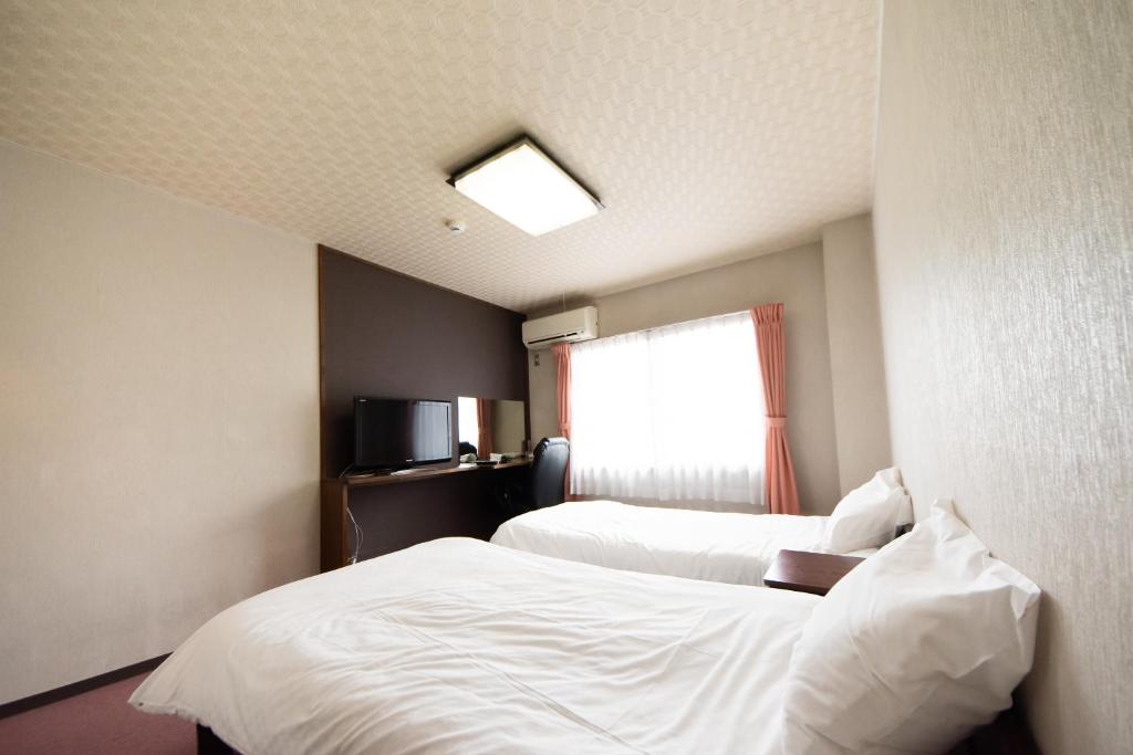 Yamato Saidaiji Hotel SINDAI في نارا: غرفة فندقية بسريرين ونافذة