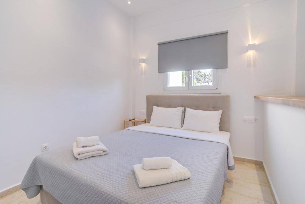 Un dormitorio blanco con una cama con toallas. en Gorgeous Mykonian Apt in Ano Mera, en Ano Mera