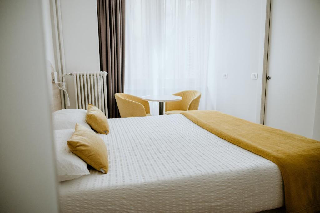 een slaapkamer met 2 bedden, een tafel en een raam bij Hotel Venezia in Trento