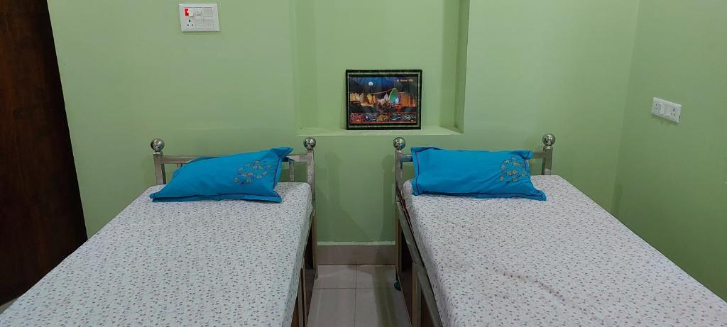 2 Betten in einem Krankenhauszimmer mit blauen Kissen in der Unterkunft Anand Bhavan in Deoghar