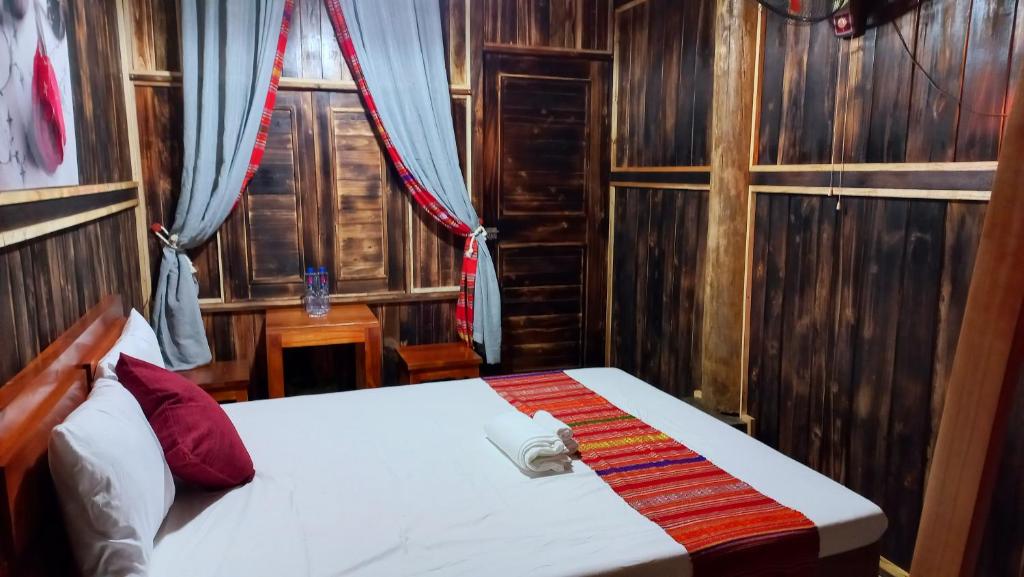 a bedroom with a bed in a room with wooden walls at Puluong Bao Gia Homestay in Làng Bang