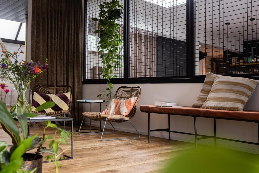 a bench and chairs in a room with plants at WOWieGermain Luxueus vakantiehuis voor families, vlak bij het strand in Oostduinkerke