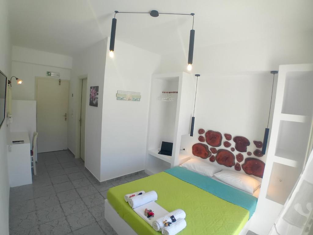a white room with a bed with a green and white bed sqor at Nikolas ios Village in Ios Chora