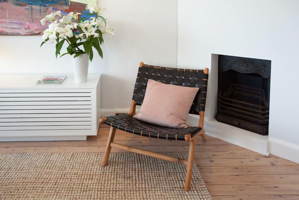 a chair with a pillow in a room with a fireplace at Barefoot in Bronte IH in Sydney