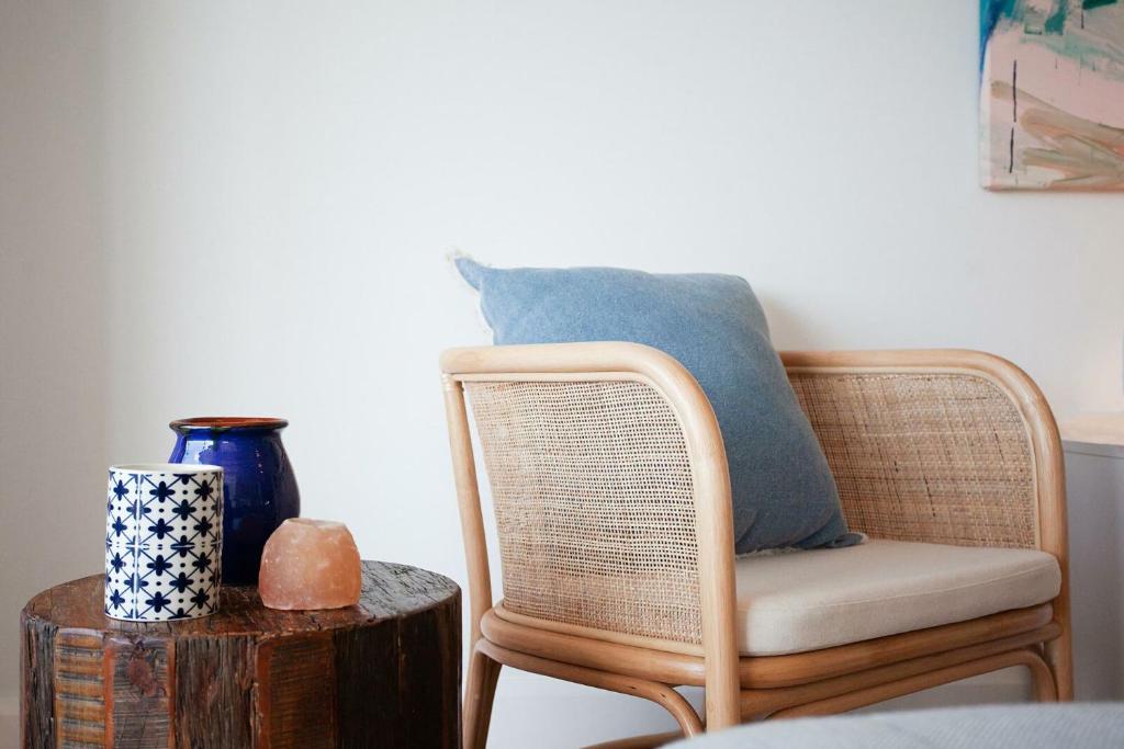 a rattan chair with a blue pillow and a table at Barefoot in Bronte IH in Sydney