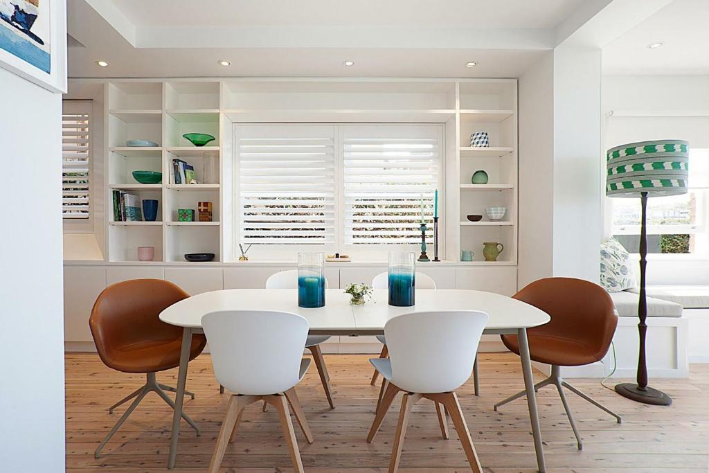a dining room with a white table and chairs at Barefoot in Bronte IH in Sydney