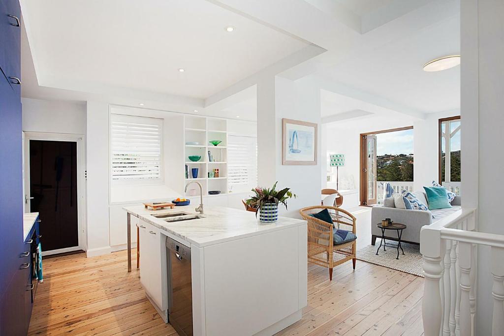 a kitchen with white countertops and a living room at Barefoot in Bronte IH in Sydney
