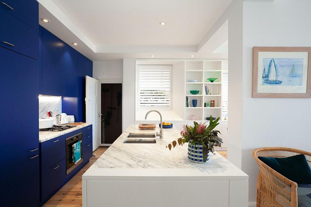 a kitchen with blue cabinets and a white counter top at Barefoot in Bronte IH in Sydney