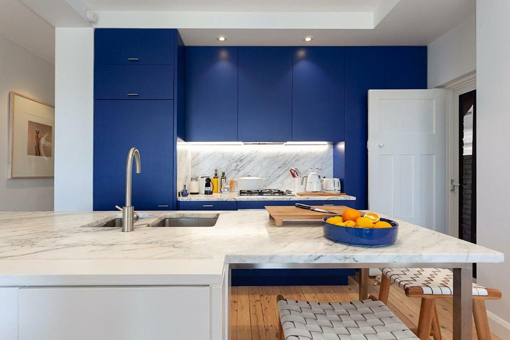 a kitchen with blue cabinets and a bowl of oranges on a counter at Barefoot in Bronte IH in Sydney