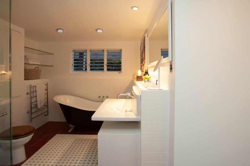 a bathroom with a tub and a toilet and a sink at Barefoot in Bronte IH in Sydney