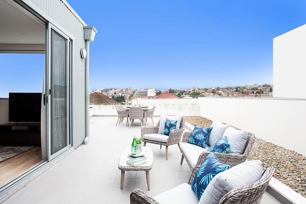 a patio with a couch and chairs on a balcony at Bream Penthouse in Sydney