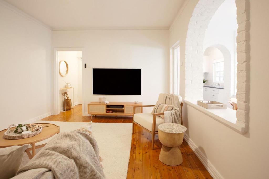 een woonkamer met een flatscreen-tv aan de muur bij Coastal Calm Coogee in Sydney