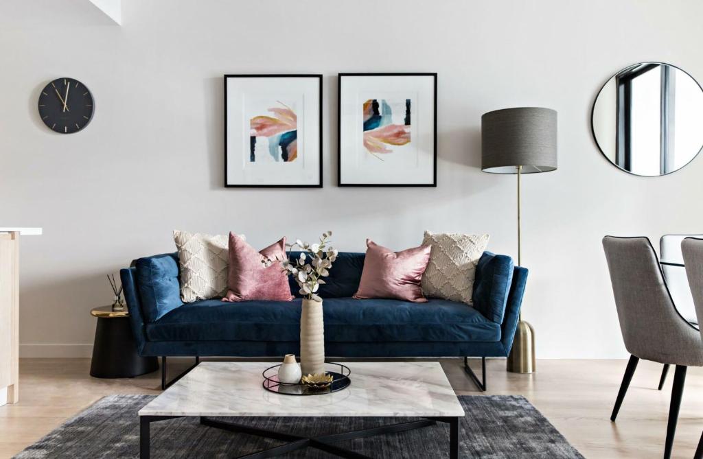 a living room with a blue couch and three pictures on the wall at Cosmopolitan Heights in Sydney