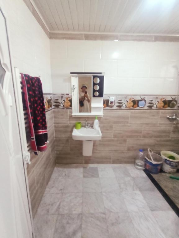 ein Bad mit einem Waschbecken und einem Spiegel in der Unterkunft EL SARAYA M'SILA DZ in MʼSila
