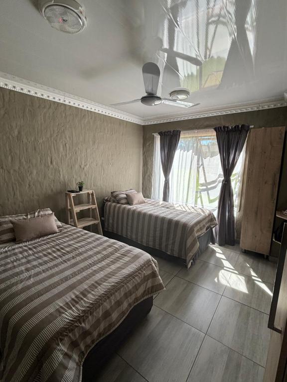 a bedroom with two beds and a window at Farmers Lodge in Piet Retief
