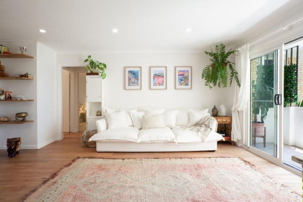 sala de estar con sofá blanco y alfombra en La Brisa Coogee, en Sídney