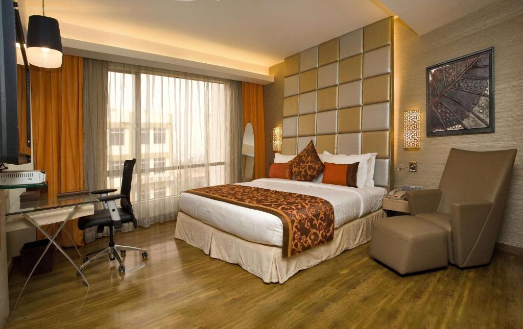 Hotel Park Seven Near Delhi International Airport في نيودلهي: غرفة في الفندق مع سرير ومكتب
