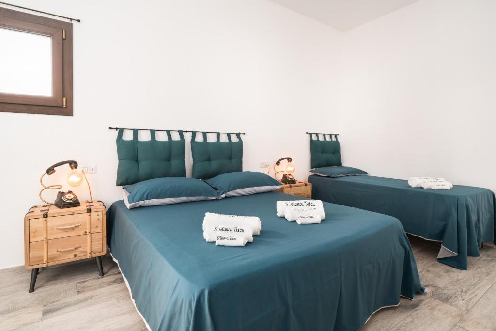 2 bedden in een slaapkamer met blauwe lakens en handdoeken bij S' Istancu Vetzu in Irgoli