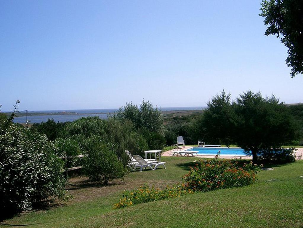 a yard with a swimming pool and trees and a field at Villa Serena A in Stintino