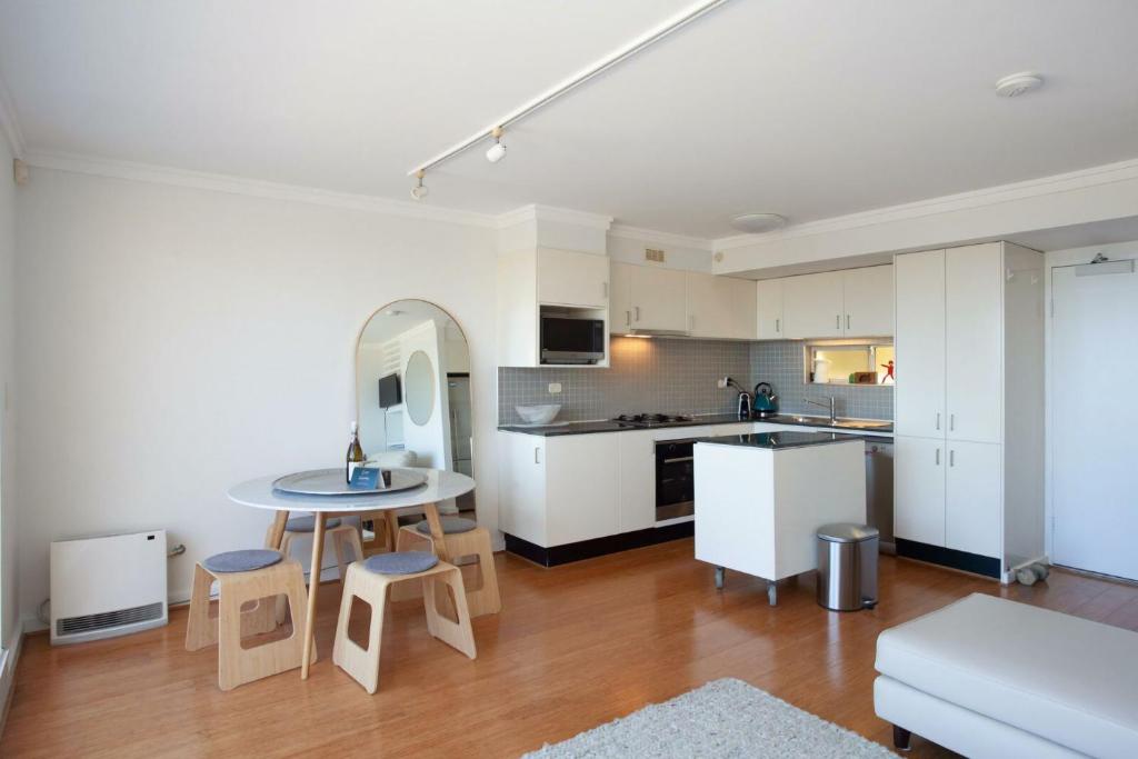 a kitchen with white cabinets and a table and chairs at Ocean view Clovelly in Sydney