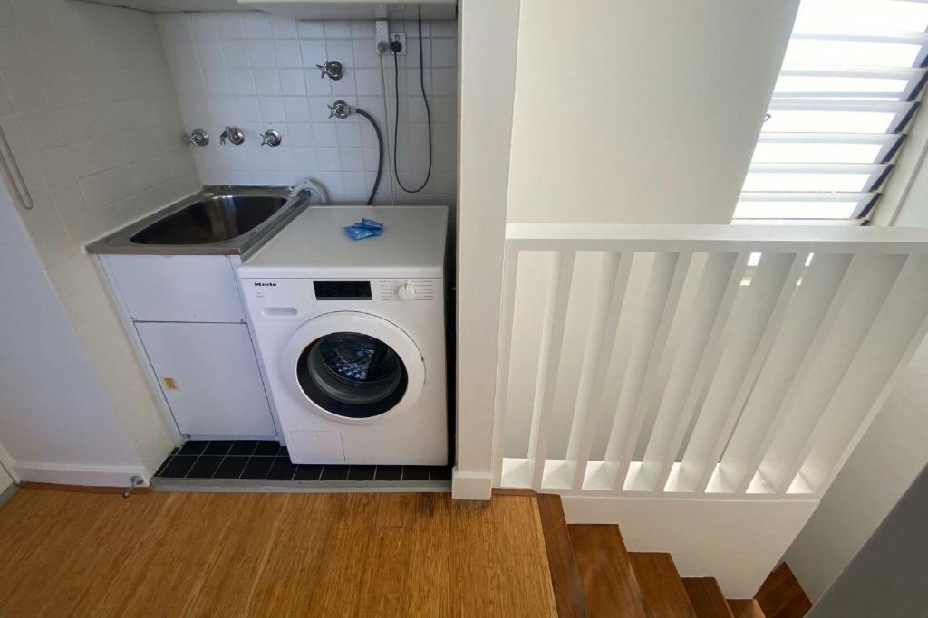 a small bathroom with a washing machine and a sink at Ocean view Clovelly in Sydney