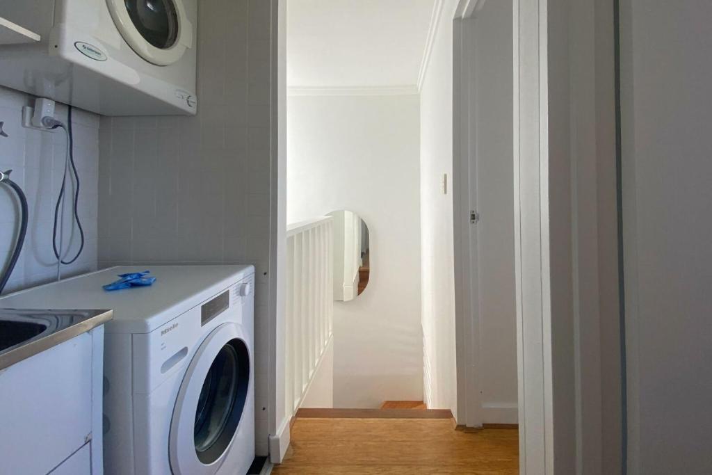 a laundry room with a washer and a washing machine at Ocean view Clovelly in Sydney