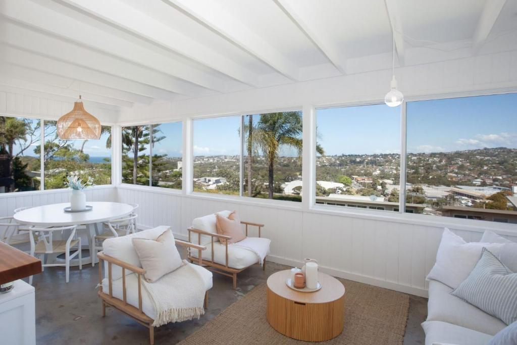 uma sala de estar com mobiliário branco e janelas grandes em Palm Springs in Collaroy em Collaroy