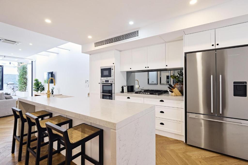 a kitchen with white cabinets and a stainless steel refrigerator at Royal Redfern Isyd in Sydney
