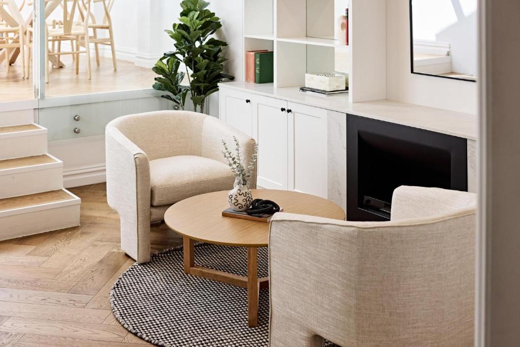 a living room with two chairs and a table and a tv at Royal Redfern Isyd in Sydney