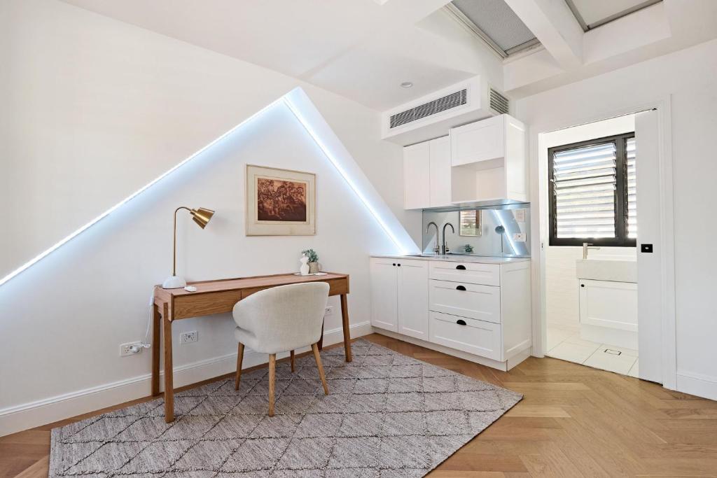 a white kitchen with a desk and a sink at Royal Redfern Isyd in Sydney
