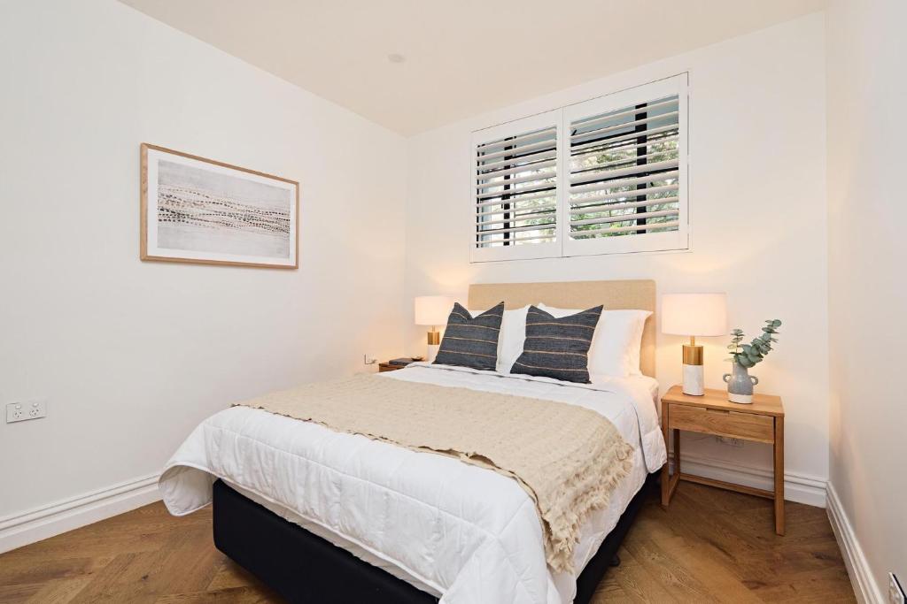 a white bedroom with a bed and a window at Royal Redfern Isyd in Sydney