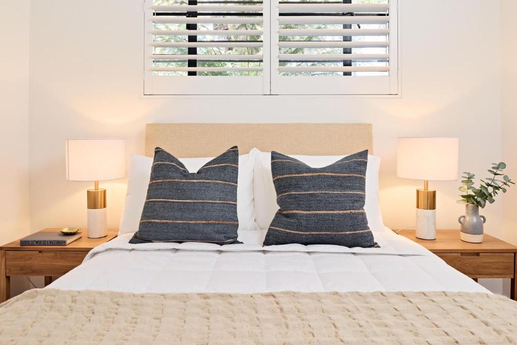 a bedroom with a bed with pillows and two lamps at Royal Redfern Isyd in Sydney