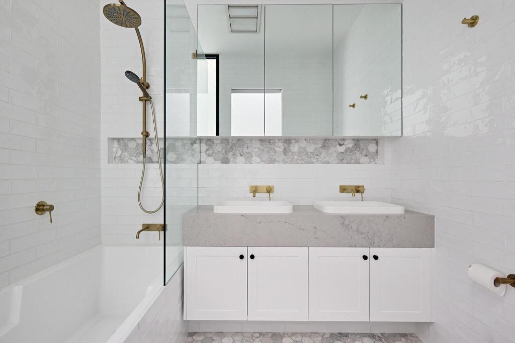 a white bathroom with two sinks and a shower at Royal Redfern Isyd in Sydney