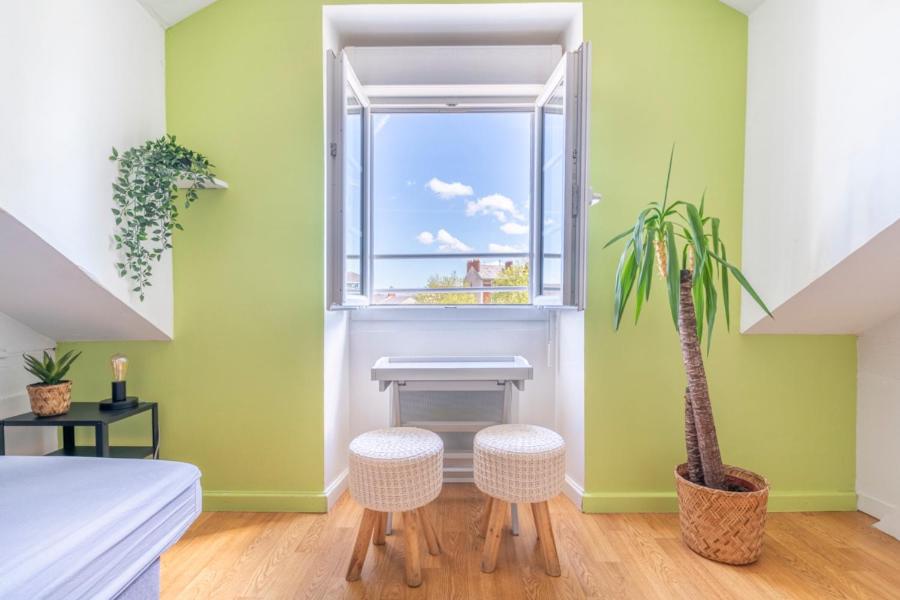 a bedroom with a window and a table and a plant at Nid douillet au bord de l'erdre in Nantes