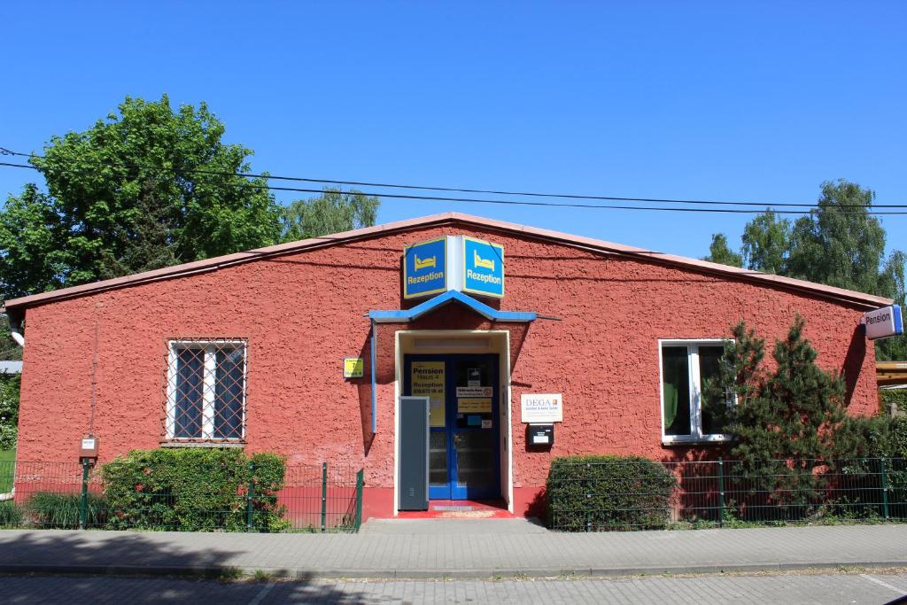 um edifício de tijolos vermelhos com um sinal azul por cima da porta em Pension Schwalbenweg em Schönefeld
