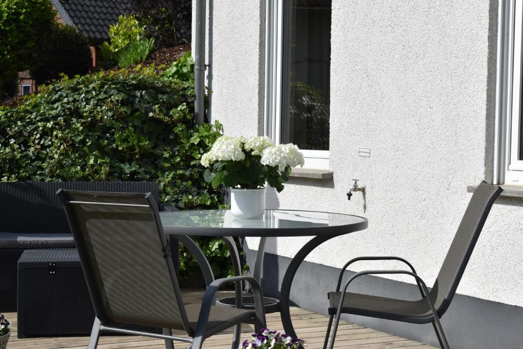 una mesa y sillas en un patio con un jarrón de flores en Ferienwohnung Reis, en Sankt Aldegund