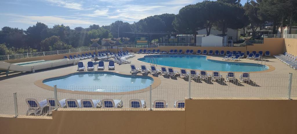 una vista panoramica su due piscine con sedie e tavoli di Domaine Résidentiel de Plein Air Odalys La Pinède ad Agde