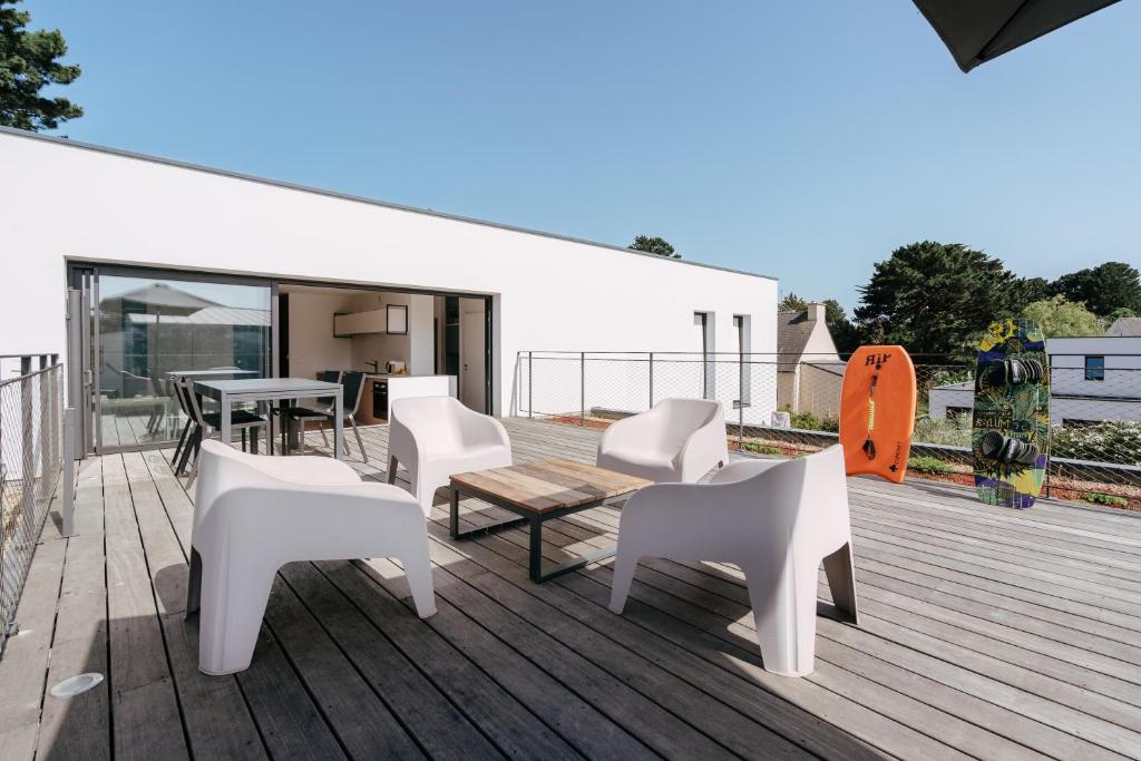 une terrasse avec des chaises blanches, une table et un skateboard dans l'établissement Arradon Plage et Bourg, à Arradon