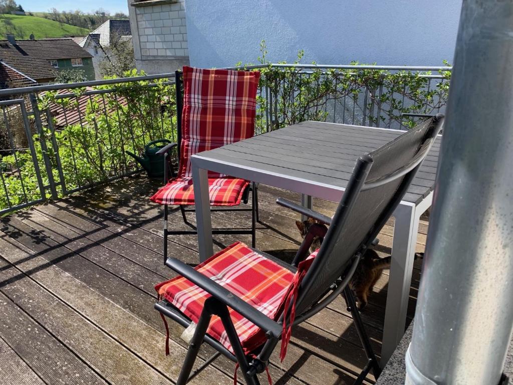 a table and two chairs on a deck with a dog at Fewo Max in Münchweier
