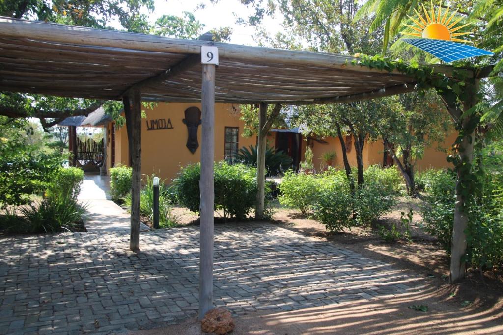 drewniana pergola z parkometrem i budynkiem w obiekcie Bushvilla Umoja Kruger w mieście Phalaborwa