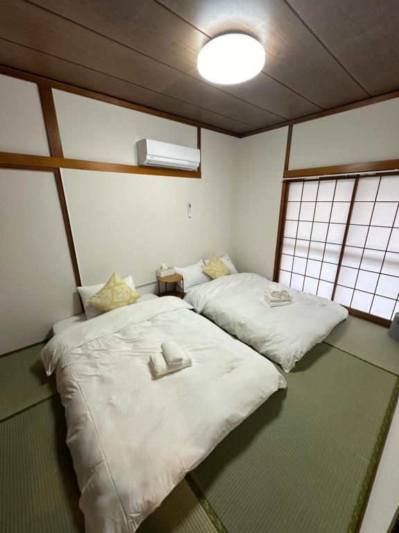 - 2 lits dans une chambre avec 2 fenêtres dans l'établissement 桜Home, à Tokyo