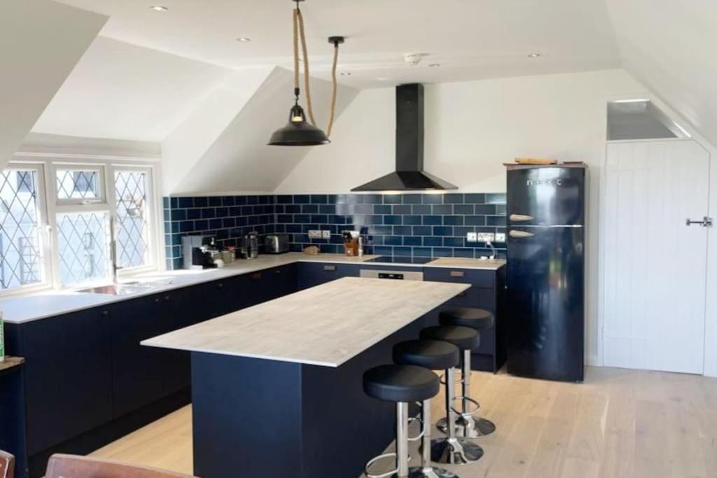 a kitchen with blue cabinets and a black refrigerator at Modern, centrally located, beach view flat in Pevensey