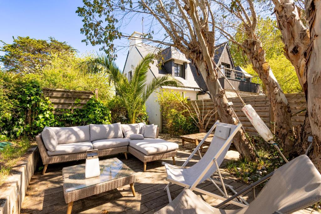 a patio with a couch and chairs and a tree at Bel appartement à 300m des plages in Carnac