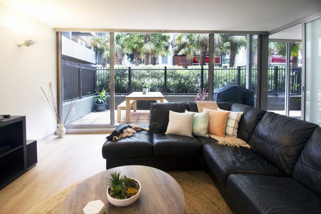 a living room with a black leather couch and a table at Urban Sea Drift in Melbourne