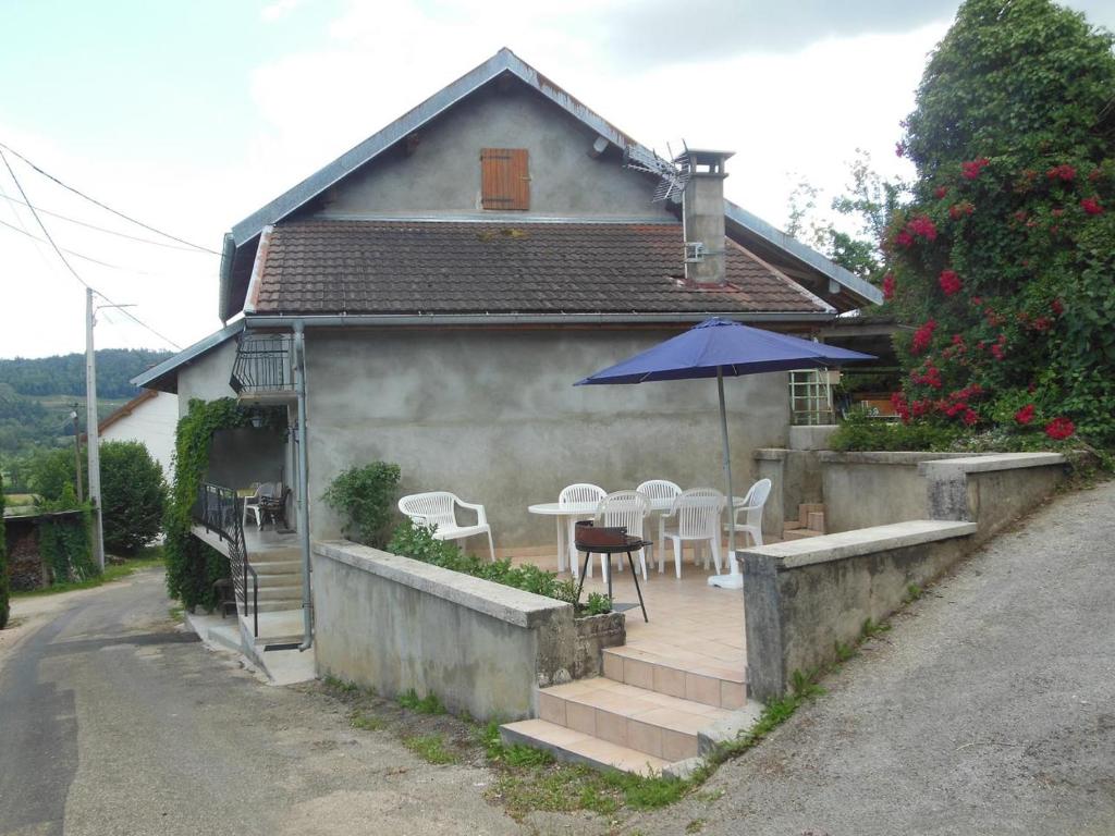 Casa con patio con mesa y sombrilla en Maison De Campagne T3 110 M en Dortan