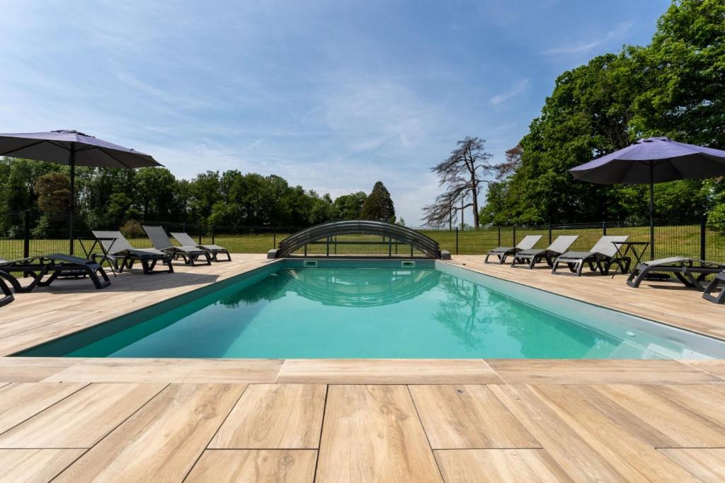 une piscine avec chaises et parasols sur un patio dans l'établissement Gite Arbois 2 pièces Piscine Chauffée, à La Châtelaine