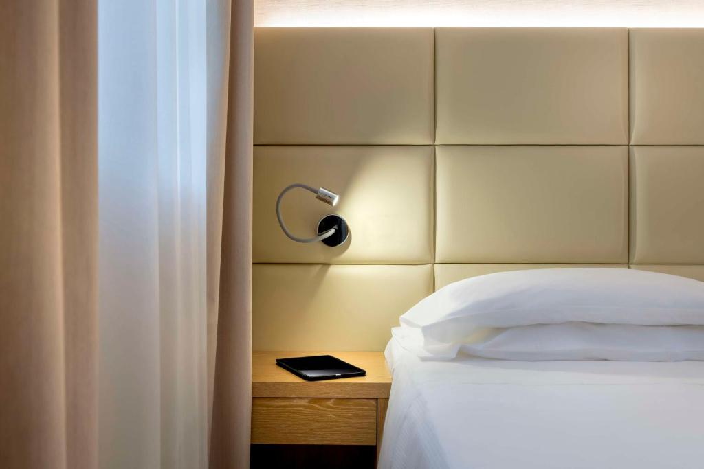 カルダーノ・アル・カンポにあるベスト   ウェスタン カサバリエリ デラ コロナのベッドルーム1室(ベッド1台、ヘッドボード、ランプ付)